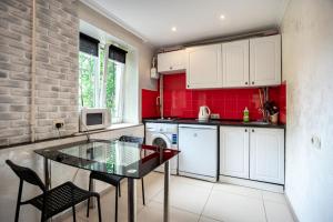 une cuisine avec une table en verre et un mur rouge dans l'établissement Studio - Koshevogo Street, à Mykolaïv