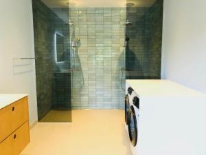 y baño con ducha y lavadora. en aday - 4 Bedroom - Modern Living Apartment - Aalborg, en Aalborg