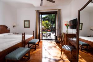 a bedroom with a bed and a desk and chairs at Parador de La Gomera in San Sebastián de la Gomera
