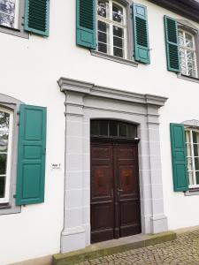 una puerta de madera en un edificio blanco con persianas verdes en Ehem. Sommerresidenz von Fürst Friedrich III. App.1 und App.2, en Kirn