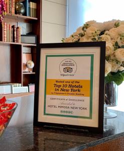 ein gerahmtes Schild auf der Theke mit einem Blumenstrauß in der Unterkunft Hotel Mimosa in New York