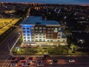 a large building with a lot of cars in a parking lot at Holiday Inn Express & Suites - Houston Westchase - Westheimer, an IHG Hotel in Houston