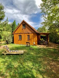 una cabaña de madera con un banco delante en Pod lipą, en Ruciane-Nida