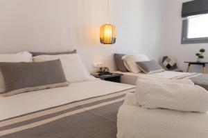 a white bedroom with two beds and a couch at Fragoulis Village in Parasporos