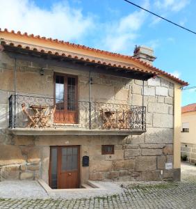 a stone house with a balcony and a door at Casa da Souropires in Pinhel