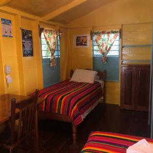 
a bedroom with a bed, chair, and window at Colinda Cabanas in Caye Caulker
