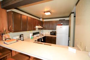 a kitchen with wooden cabinets and a white refrigerator at Mammoth Ski & Racquet Club #129 in Mammoth Lakes