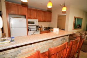 a kitchen with a counter with chairs and a refrigerator at Crestview #63 in Mammoth Lakes