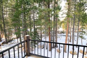 a snow covered forest with a black railing and trees at Forest Creek #3, Pet accepted in Mammoth Lakes