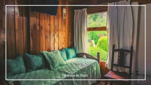 1 dormitorio con ventana y 1 cama con almohadas verdes en La Posada del Trebol en San Carlos de Bariloche