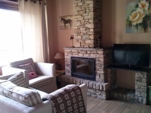 a living room with a stone fireplace and a television at Alba D'Esteve. Casa Rural in Espot