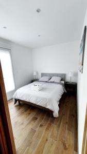 um quarto branco com uma cama e piso em madeira em "LE PAVILLON" Maisonnette 150 m gare des Aubrais em Fleury-les-Aubrais