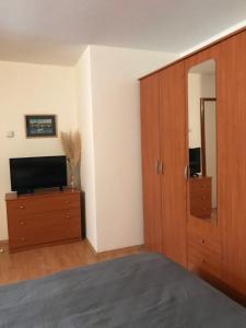 ein Wohnzimmer mit einem TV und einem Holzschrank in der Unterkunft Apartmenthaus"Kala" in Crikvenica