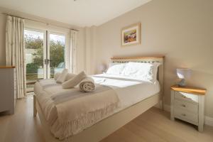 a white bedroom with a large bed and a window at Sea Folly in Perranporth