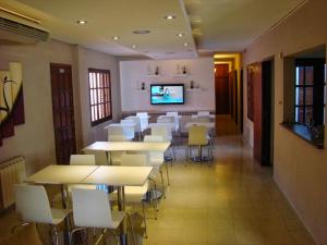 a dining room with tables and chairs and a flat screen tv at Hotel Punta Lavalle in San Luis