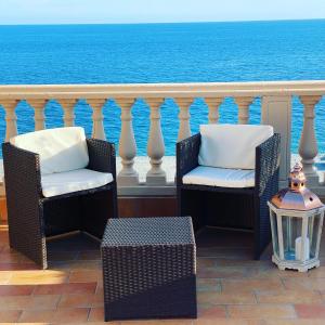 2 stoelen en een tafel op een balkon met uitzicht op de oceaan bij Le Camere di Rosanna in Marina di Gioiosa Ionica