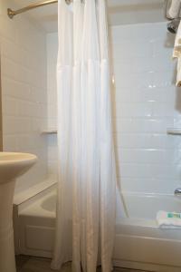 a white shower curtain in a bathroom with a tub at Hotel Pentagon in Arlington