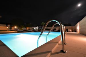 ein Schwimmbad in der Nacht mit einer Metallhand in der Unterkunft Apartmani Emili in Sukošan
