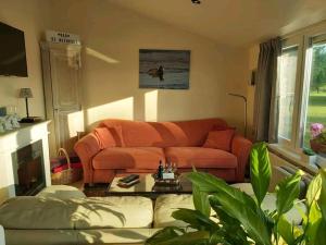 Logies De Meerkoet في Dudzele: غرفة معيشة مع أريكة برتقالية وطاولة