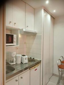 a kitchen with white cabinets and a sink and a microwave at Rive gauche in Cuffies