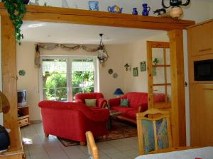 a living room with red chairs and a red couch at Huus Westerdiek in Neßmersiel