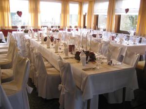 ein langer Tisch mit weißen Tischen und Stühlen in einem Raum in der Unterkunft Hotel Grauleshof in Aalen