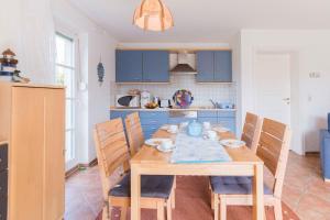 uma cozinha com uma mesa de madeira e armários azuis em Haus SWANTE WUSTROW em Wustrow