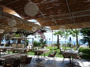 a restaurant with tables and chairs and a view of the ocean at Palmiye Hotel in Ozdere
