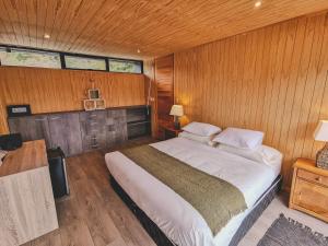 1 dormitorio con 1 cama grande en una pared de madera en Hacienda Tres Lagos, en Aldana
