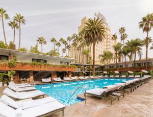 a hotel pool with lounge chairs and palm trees at The Hollywood Roosevelt in Los Angeles