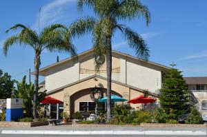 un edificio con palmeras y sombrillas delante de él en Loma Linda Inn, en San Bernardino