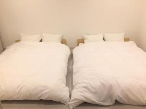 two white beds sitting next to each other at Purpose Resort Ocean View Kamakura in Kamakura