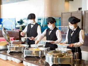three chefs wearing masks preparing food in a kitchen at Diamond Setouchi Marine Hotel in Tamano