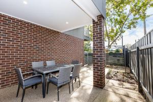 a patio with a table and chairs and a brick wall at Wagga Apartments #5 in Wagga Wagga
