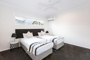 two beds in a white room with a window at Wagga Apartments #5 in Wagga Wagga