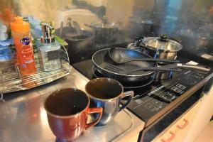 a stove top with two cups and pots and pans at KIYAZA Road Sapporo in Sapporo