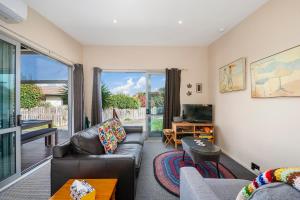 ein Wohnzimmer mit einem Sofa und einem TV in der Unterkunft Tranquil Tauhara - Taupo Central Holiday Home in Taupo