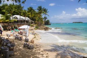 a beach with chairs and the ocean and a resort at Grand studio les pieds dans l'eau, centre ville in Le Gosier