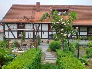 a garden in front of a house with roses at Pension Töpferhof in Bad Berka