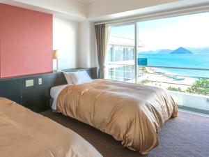 2 camas en una habitación de hotel con vistas al océano en Diamond Setouchi Marine Hotel, en Tamano
