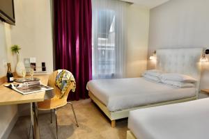 a hotel room with a bed and a desk with a desk at Hôtel Escale Oceania Lorient in Lorient