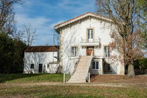 una vecchia casa bianca con le scale davanti di Maison de village -8 pers- Piscine chauffée & cuisine d'été en Gascogne a Mézin