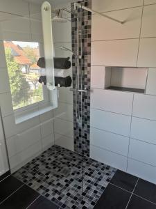 y baño con ducha y azulejos blancos y negros. en Ferienwohnung Künne, en Gevensleben