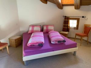ein violettes Bett in einem Zimmer mit 2 Stühlen in der Unterkunft Ferienwohnung Jalet in Tschierv
