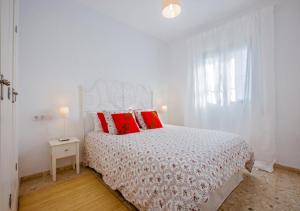 een witte slaapkamer met een bed met rode kussens bij VILLA SENSACIONES in Tarifa
