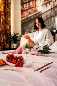 Eine Frau, die auf einem Bett mit einem Obstteller sitzt. in der Unterkunft Weekend в ЦЕНТРЕ рядом с ЖД ВОКЗАЛОМ in Krasnojarsk
