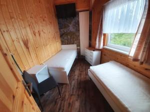 Habitación pequeña con 2 camas y ventana en Ferienhäuser in Allrode, en Thale