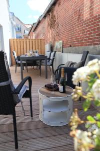 a patio with chairs and a table with a bottle of wine at Hafenperle am Suhrenpohl in Heiligenhafen