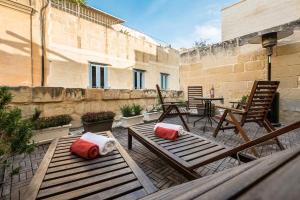 un patio con 2 bancos, mesa y sillas en Valletta Ajkla Mansion, en La Valeta