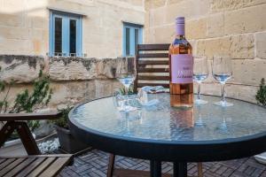 a bottle of wine sitting on a table with wine glasses at Valletta Ajkla Mansion in Valletta